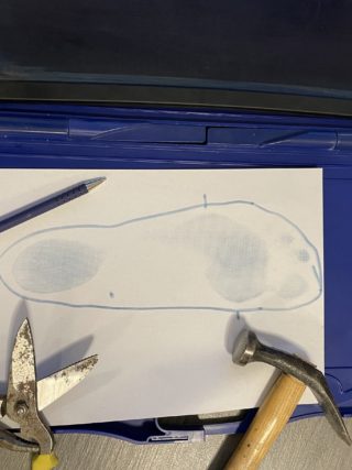 ein Blauabdruckkasten zum Maßnehmen für Einlagen daneben ein Hammer, eine Lederschere und Kugelschreiber