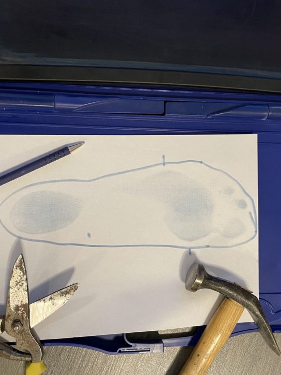 ein Blauabdruckkasten zum Maßnehmen für Einlagen daneben ein Hammer, eine Lederschere und Kugelschreiber